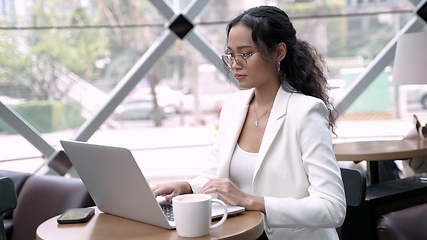 Image showing Businesswoman Using Wireless Tech and Laptop While Enjoying Coffee