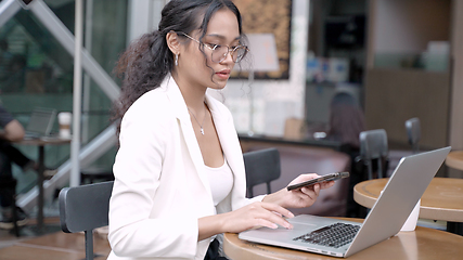 Image showing Professional Asian Businesswoman Using Mobile Phone at Cafe Table