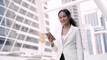 Image showing Asian executive working woman holding and using mobile phone in the street