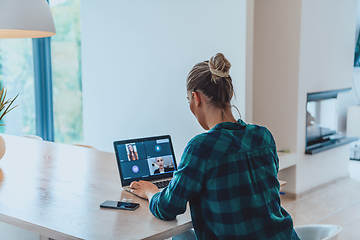 Image showing Woman sitting in living room using laptop look at cam talk by video call with business friend relatives, head shot. Job interview answering questions.