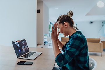 Image showing Woman sitting in living room using laptop look at cam talk by video call with business friend relatives, head shot. Job interview answering questions.