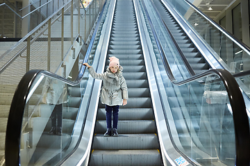 Image showing From below shot of girl standing on moving stairs in terminal.