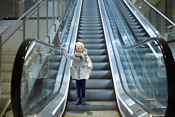 Image showing From below shot of girl standing on moving stairs in terminal.