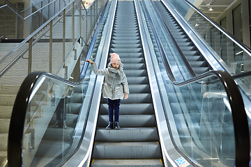 Image showing From below shot of girl standing on moving stairs in terminal.