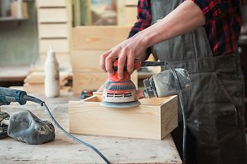 Image showing Worker grinds the wood box