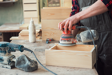 Image showing Worker grinds the wood box