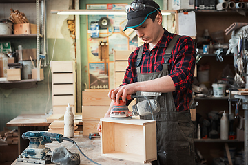 Image showing Worker grinds the wood box