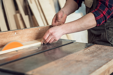 Image showing Construction worker cutting wooden board