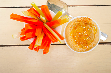 Image showing fresh hummus dip with raw carrot and celery