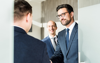 Image showing Group of confident business people greeting with a handshake at business meeting in modern office or closing the deal agreement by shaking hands.