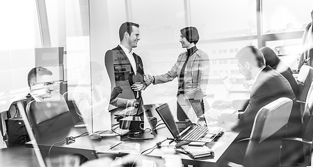 Image showing Confident business people shaking hands in moder corporate office.