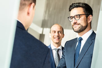 Image showing Group of confident business people greeting with a handshake at business meeting in modern office or closing the deal agreement by shaking hands.