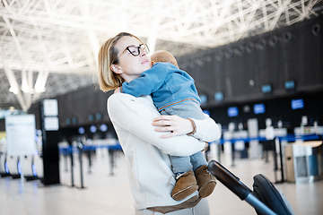 Image showing Motherat happily holding and lifting his infant baby boy child in the air after being rejunited in front of airport terminal station. Baby travel concept.