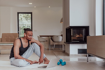 Image showing Training At Home. Sporty man doing training while watching online tutorial on laptop, exercising in living room, free space