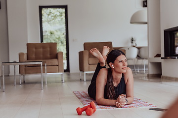 Image showing Young woman resting after online training while lying on the living room floor