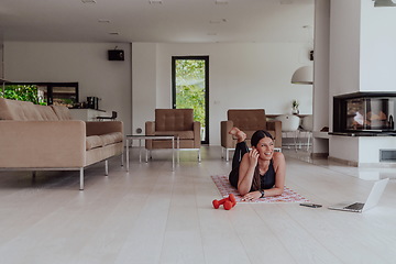 Image showing Young woman resting after online training while lying on the living room floor