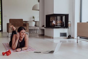 Image showing Young woman resting after online training while lying on the living room floor