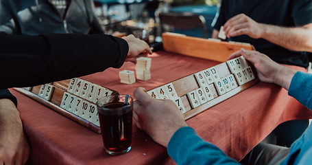 Image showing A group of men drink traditional Turkish tea and play a Turkish game called Okey