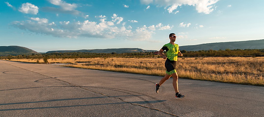 Image showing Triathlete in professional gear running early in the morning, preparing for a marathon, dedication to sport and readiness to take on the challenges of a marathon.