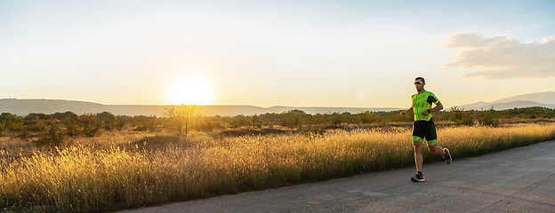 Image showing Triathlete in professional gear running early in the morning, preparing for a marathon, dedication to sport and readiness to take on the challenges of a marathon.