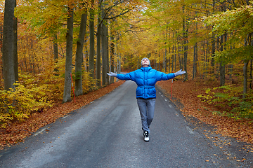 Image showing Young woman posing in the autumn forest on the road.