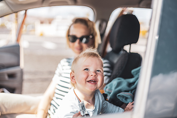 Image showing Mother and her infant baby boy child on family summer travel road trip, sitting at dad's front seat, waiting in the car for father to buy farry tickets.
