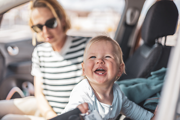 Image showing Mother and her infant baby boy child on family summer travel road trip, sitting at dad's front seat, waiting in the car for father to buy farry tickets.