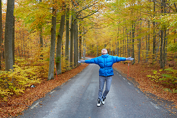 Image showing Young woman posing in the autumn forest on the road.