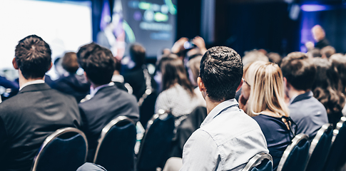 Image showing Speaker giving a talk in conference hall at business event. Rear view of unrecognizable people in audience at the conference hall. Business and entrepreneurship concept.