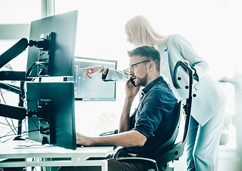 Image showing Stock broker business team trading online watching charts and data analyses on multiple computer screens in modern corporate work station office.