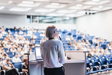 Image showing Female speaker giving a talk on corporate business conference. Unrecognizable people in audience at conference hall. Business and Entrepreneurship event.