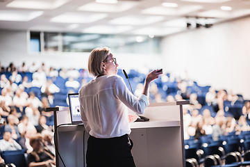 Image showing Female speaker giving a talk on corporate business conference. Unrecognizable people in audience at conference hall. Business and Entrepreneurship event.