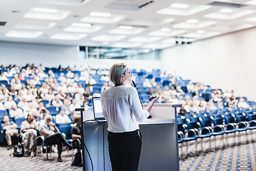 Image showing Female speaker giving a talk on corporate business conference. Unrecognizable people in audience at conference hall. Business and Entrepreneurship event.