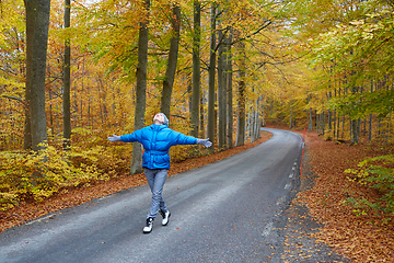 Image showing Young woman posing in the autumn forest on the road.