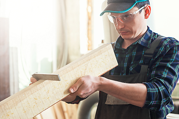 Image showing The worker makes measurements of a wooden board