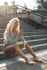 Image showing beauty blonde young woman sitting on outdoor and eating