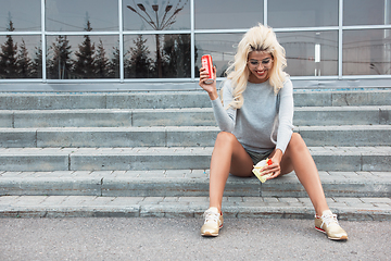 Image showing beauty blonde young woman sitting on outdoor and eating