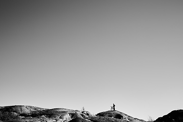 Image showing Silhouette of young active man with bicycle standing and looking forward at mountains panoramic background