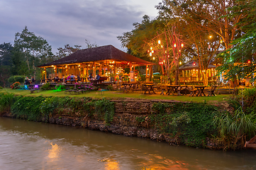 Image showing Illuminated outdoor restaurant by river