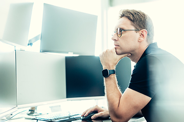 Image showing Stock broker trading online watching charts and data analyses on multiple computer screens.