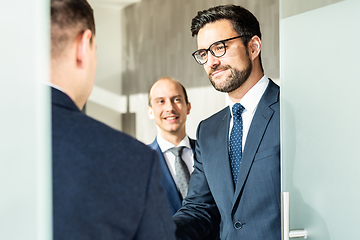 Image showing Group of confident business people greeting with a handshake at business meeting in modern office or closing the deal agreement by shaking hands.