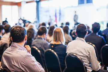 Image showing Speaker giving a talk in conference hall at business event. Rear view of unrecognizable people in audience at the conference hall. Business and entrepreneurship concept.