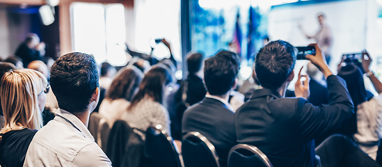 Image showing Speaker giving a talk in conference hall at business event. Rear view of unrecognizable people in audience at the conference hall. Business and entrepreneurship concept.