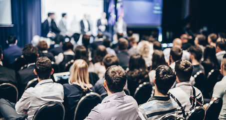 Image showing Speaker giving a talk in conference hall at business event. Rear view of unrecognizable people in audience at the conference hall. Business and entrepreneurship concept.