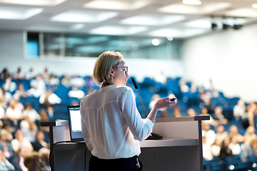 Image showing Female speaker giving a talk on corporate business conference. Unrecognizable people in audience at conference hall. Business and Entrepreneurship event.