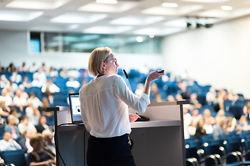 Image showing Female speaker giving a talk on corporate business conference. Unrecognizable people in audience at conference hall. Business and Entrepreneurship event.