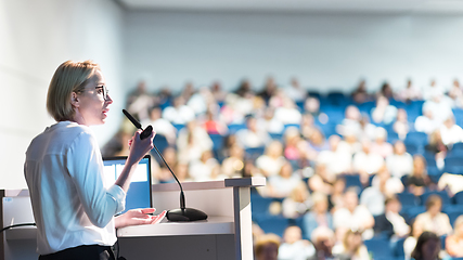 Image showing Female speaker giving a talk on corporate business conference. Unrecognizable people in audience at conference hall. Business and Entrepreneurship event.