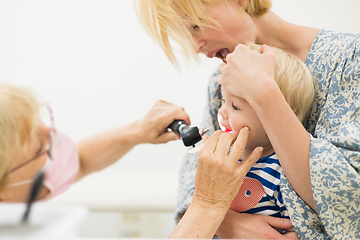 Image showing Infant baby boy child being examined by his pediatrician doctor during a standard medical checkup in presence and comfort of his mother. National public health and childs care care koncept.