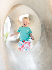 Image showing Child playing on outdoor playground. Toddler plays on school or kindergarten yard. Active kid on stone sculpured slide. Healthy summer activity for children. Little boy climbing outdoors.