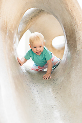 Image showing Child playing on outdoor playground. Toddler plays on school or kindergarten yard. Active kid on stone sculpured slide. Healthy summer activity for children. Little boy climbing outdoors.